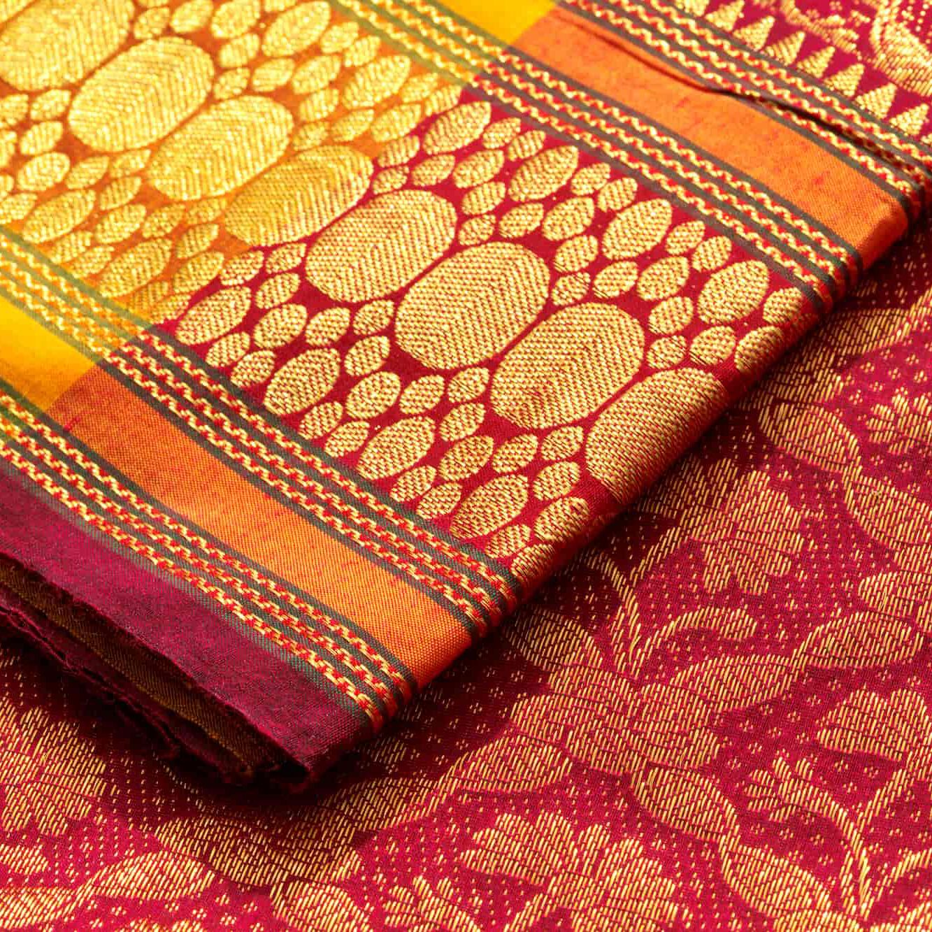 Close-up of a richly woven red and gold silk saree with intricate patterns and borders, showcasing traditional Indian textile craftsmanship.